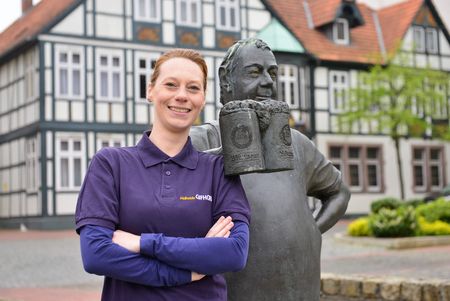 Frau mit verschränkten Armen neben der Bierbrauer-Statur.