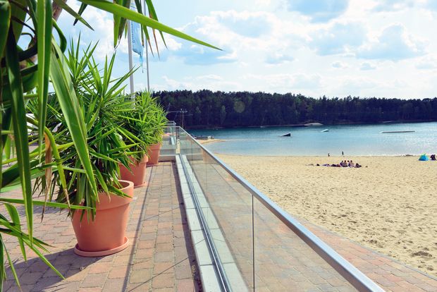 Terrasse am Bernsteinsee mit Blumentöpfen, Strand und Wasser bei Gifhorn. 