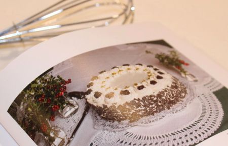 Aufgeschlagenes Backbuch mit einer abgebildeten Schwarzwälderkirschtorte und Schneebesen.