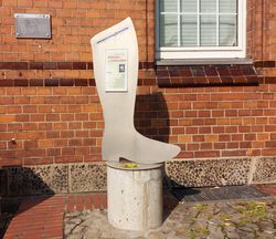 Übergroßer Schusterstiefel mit Beschreibungstafel vor einer Gebäude in Wittingen.