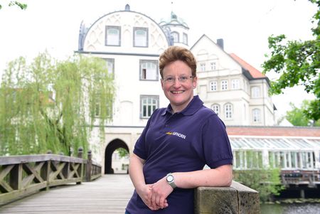 Frau lehnt an der Holzbrück vor dem Gifhorner Welfenschloss.