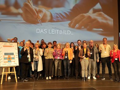 Personengruppe auf der Bühne während der Unterzeichnung des Nachhaltigkeitsleitbildes der aboutcities.