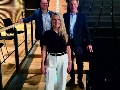 Die Geschäftsführungen der Südheide Gifhorn GmbH und der Stadthalle Gifhorn GmbH stehen in einem Aufgang der Stuhlreihen der Gifhorner Stadthalle und präsentieren die gemeinsamen Kulturarrangements.