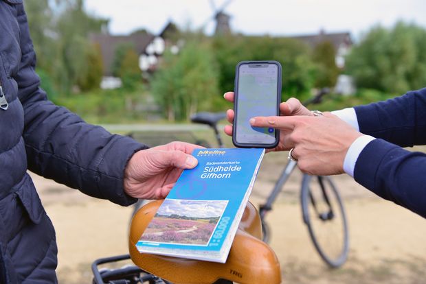 Ein Mann und eine Frau halten eine Radkarte und ein Handy in der Hand.