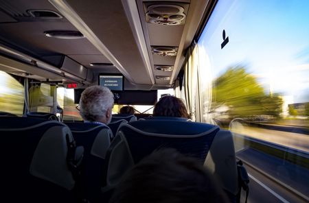 Ein Mann und eine Frau sitzen im Reisebus in Fahrtrichtung.