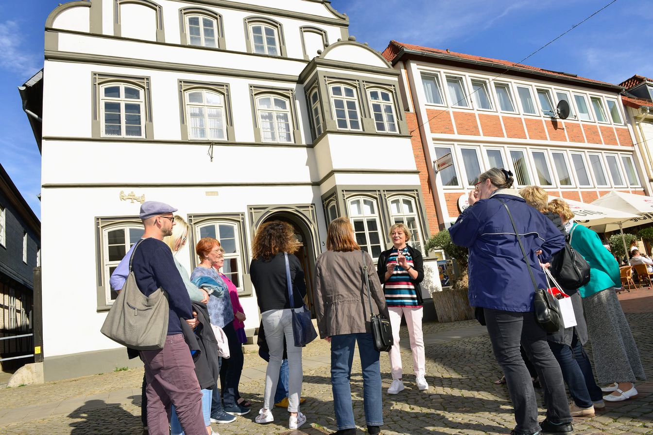 Eine Gästeführerin mit einer Stadtführungsgruppe vor dem Gifhorner Kavalierhaus.