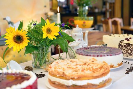 Verschiedene Torten und ein Strauß Sonnenblumen stehen auf einem Tisch im Café.