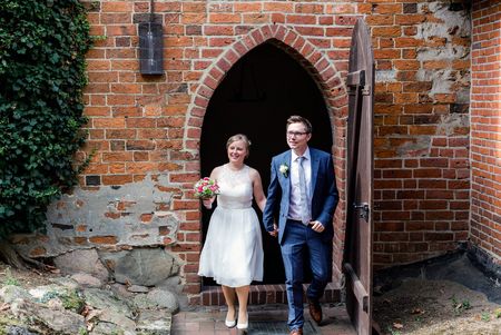 Ein Brautpaar steht vor einer geöffneten Tür vor dem Kloster Isenhagen.