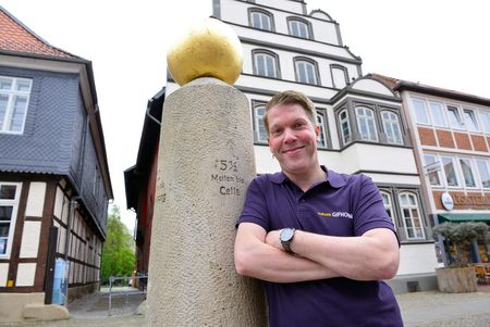 Mann mit verschränkten Armen lehnt an einer Säule.