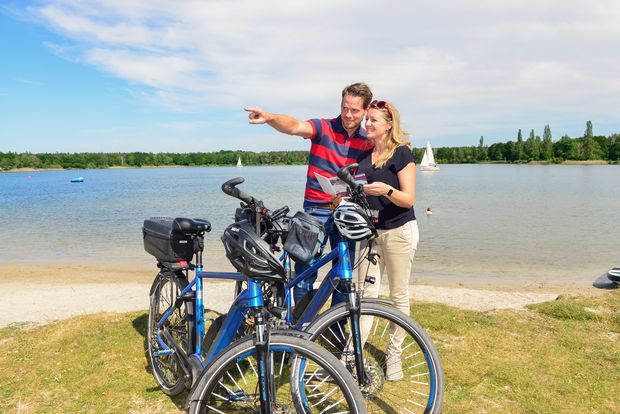 Ein Mann und eine Frau mit zwei Fahrrädern am Strand am Tankumsee.
